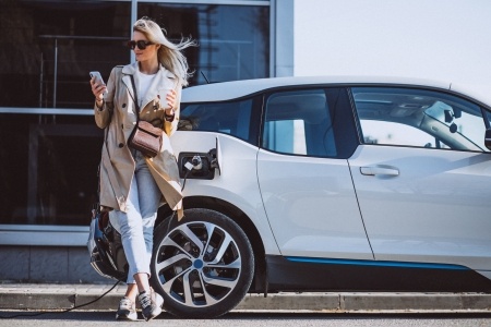 woman waiting for electric car to charge
